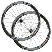 Two overlapping black and gray HED Vanquish V45 Carbon Aero wheels with thin spokes, visible hub mechanisms, and sleek aerodynamic rims are arranged against a white background, highlighting the advanced design of this premium carbon wheelset tailored for all-road riding.