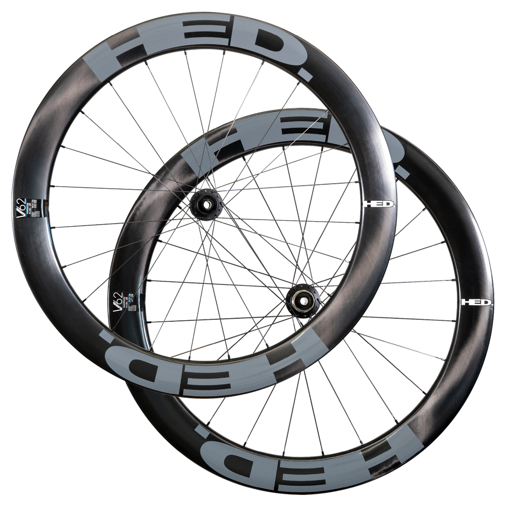 Two HED Vanquish V62 Carbon Aero Wheels in black and gray, featuring deep-section, aerodynamic carbon rims, are shown overlapping against a plain white background—an ideal high-performance wheelset for triathlon riders.