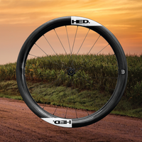 Bicycle wheel with 'HED' branding on a dirt road with grass and sunset sky
